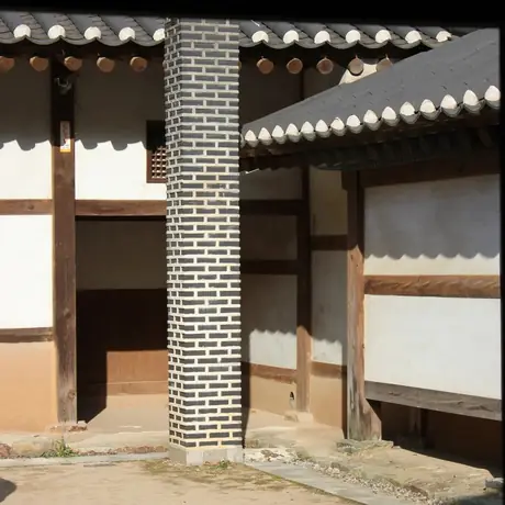 A patterned brick chimney set between two tiled hanok wings