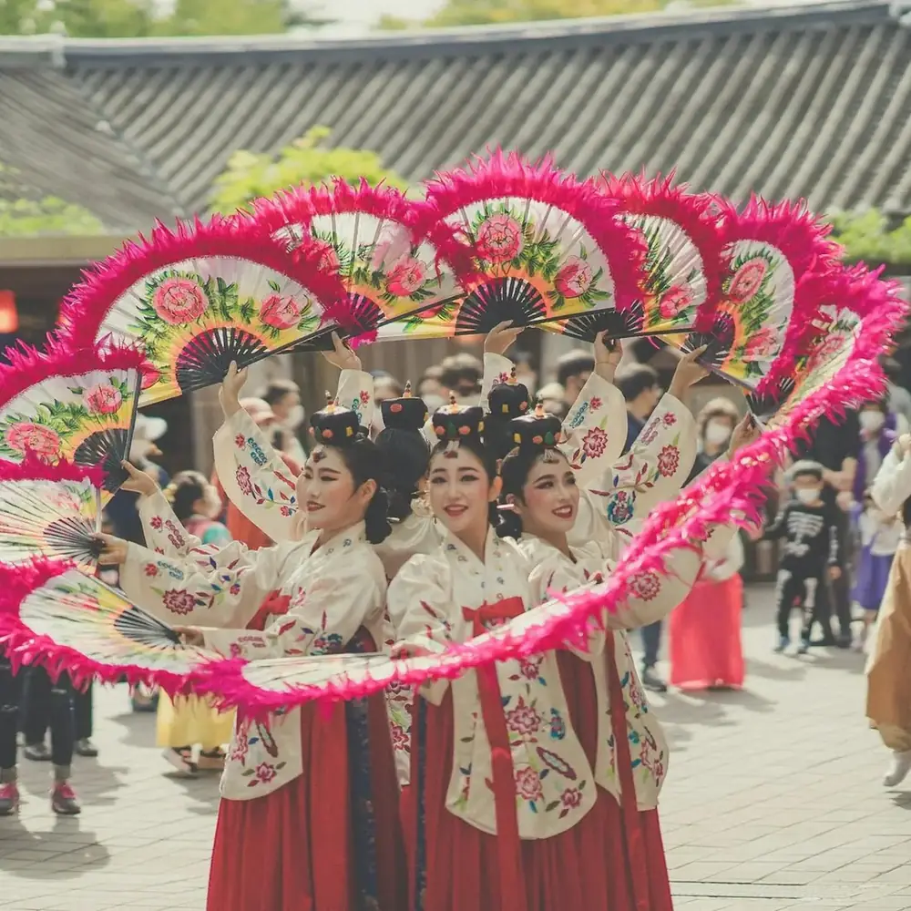 Dancers in hanbok performing a fan dance in a festival procession