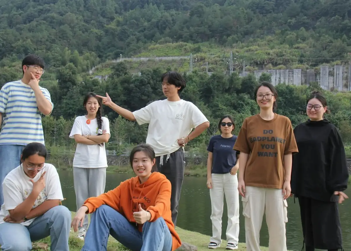 A group of friends together beside a lake, mountains behind them